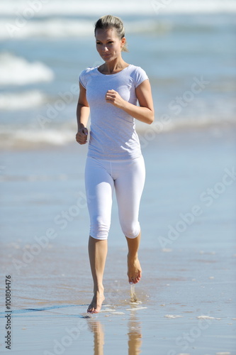 young woman jogging on the beach in summer sunny day