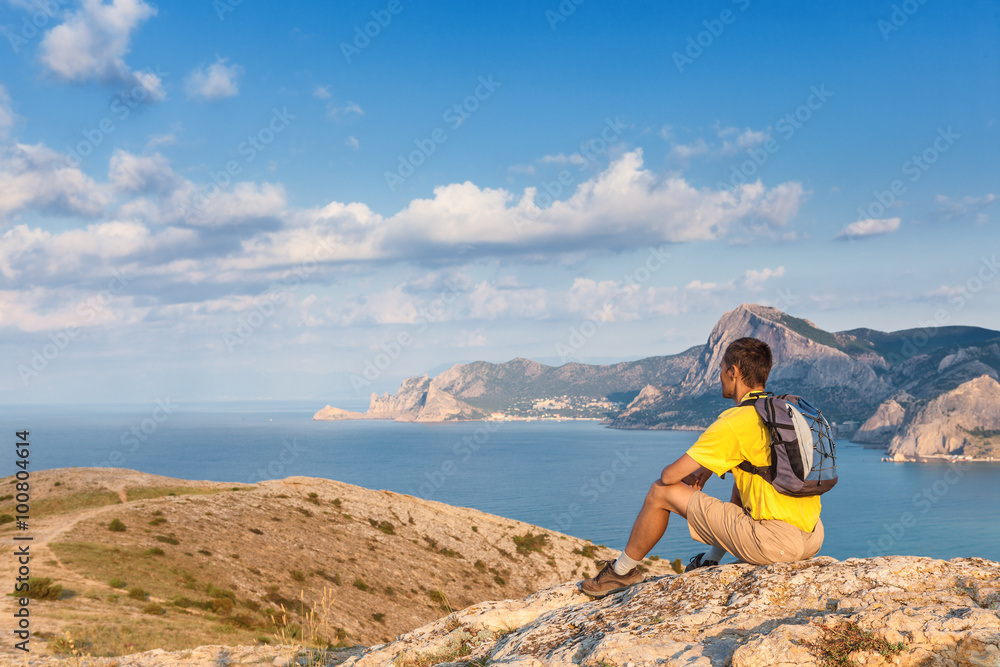 man with backpack sitting on a rock