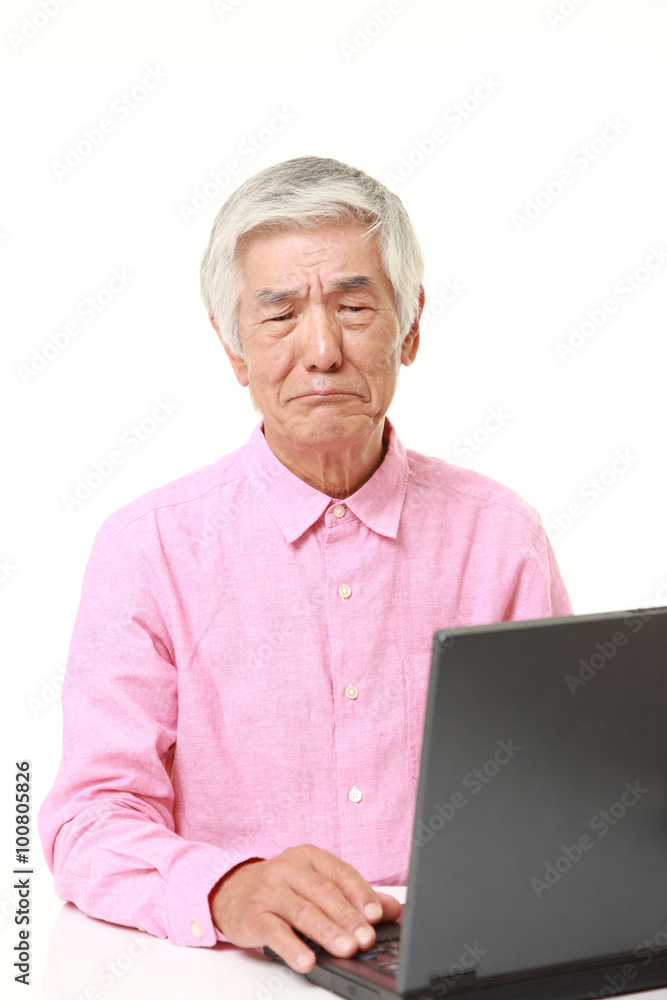 senior Japanese man using computer looking confused senior Japanese man using computer looking confused