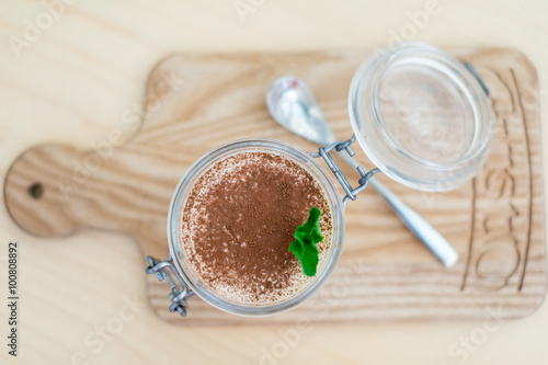 dessert with fruits, nuts and cream cheese in glass jar on wooden background