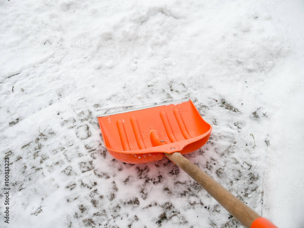 Snow removal. Orange Shovel in snow, ready for snow removal, outdoors.