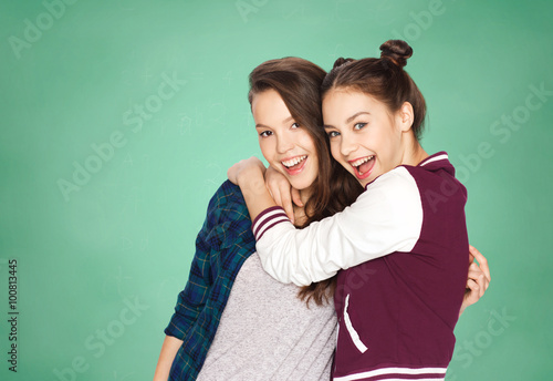 happy teenage girls hugging over green board