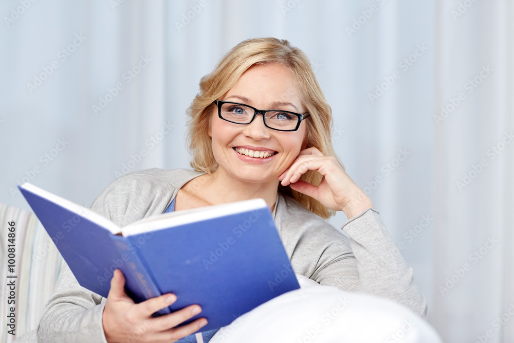 smiling woman reading book and sitting on couch smiling woman reading book and sitting on couch