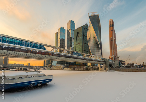 Пешеходный мост Багратион на фоне высотных зданий Делового центра Москва-Сити зимой на закате.