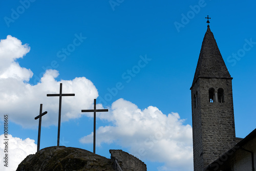 Crosses and Church Silhouette Against Sky / Silhouette of three crosses and a church with bell tower against a blue sky with clouds. Carisolo Trentino Italy photo