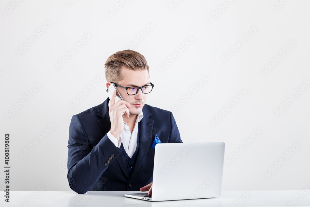 Young businessman working in office, sitting at desk, looking at laptop computer Young businessman working in office, sitting at desk, looking at laptop computer