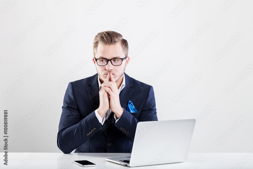 Young businessman working in office, sitting at desk, looking at laptop computer Young businessman working in office, sitting at desk, looking at laptop computer