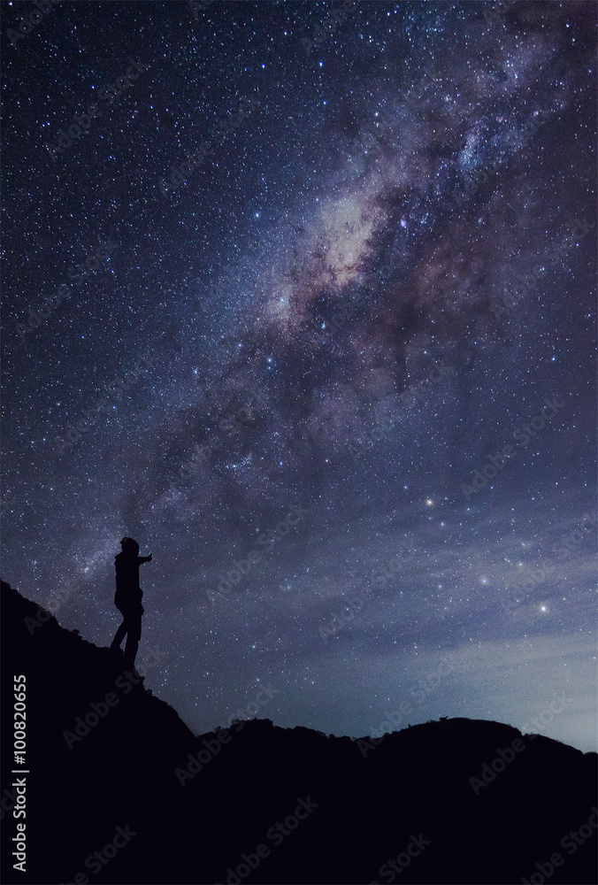 A person is standing next to the Milky Way galaxy thump up on a
