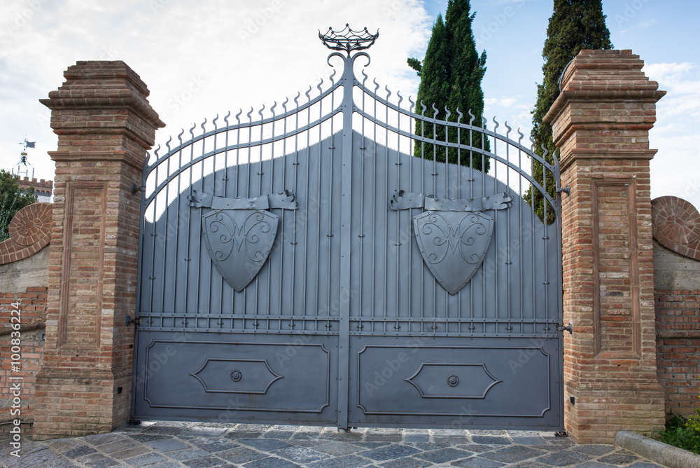 Naklejka premium Cancello di ferro con scudi, ingresso a villa