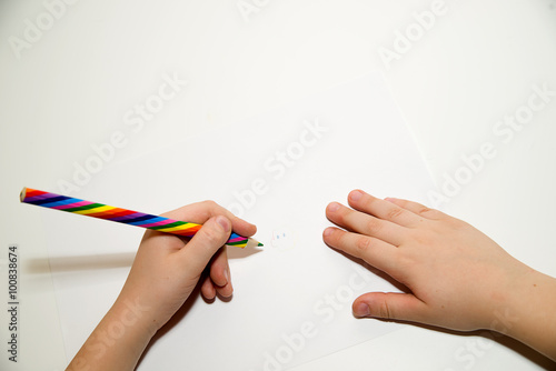 Kid's  hands holding a pencil on over white photo