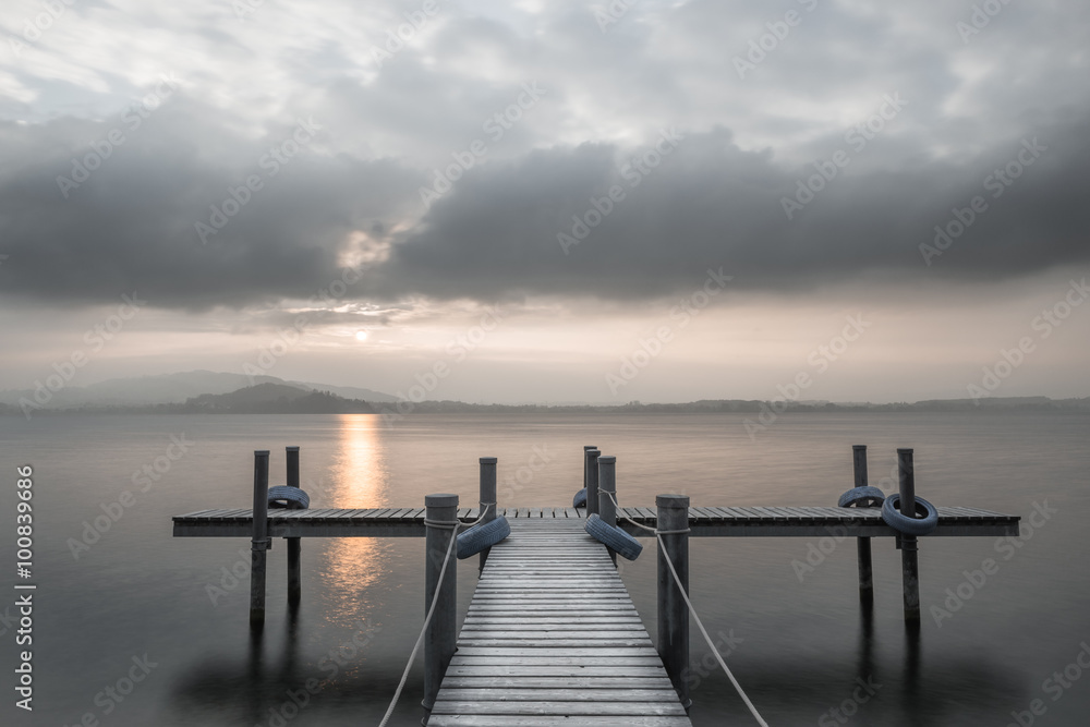Wooden pier on the lake. Fog. Sunset in pastel colors. Long exposure.