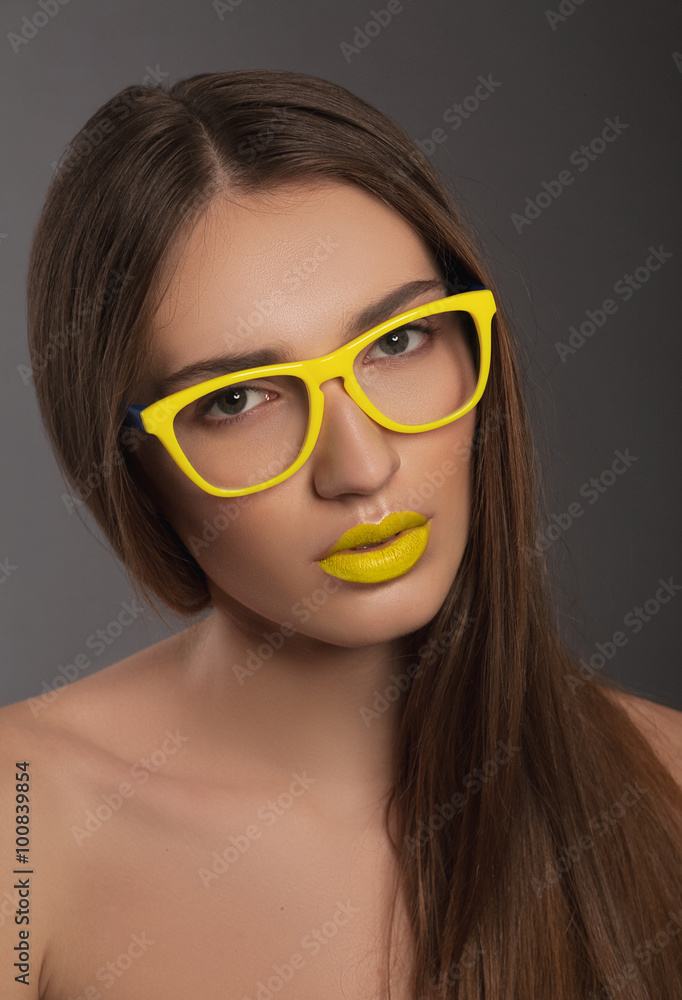 Beauty woman face portrait with yellow lips in yellow sunglasses Beauty woman face portrait with yellow lips in yellow sunglasses