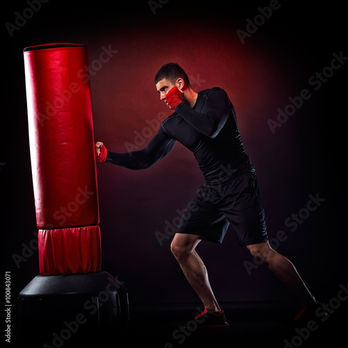 young man exercising bag boxing in studio photo