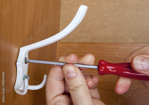 Triple white coat hook attached screw in wooden wardrobe. photo