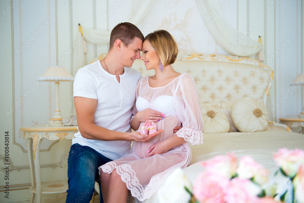 Happy Pregnancy: husband holding baby booties near the belly his pregnant wife Happy Pregnancy: husband holding baby booties near the belly his pregnant wife