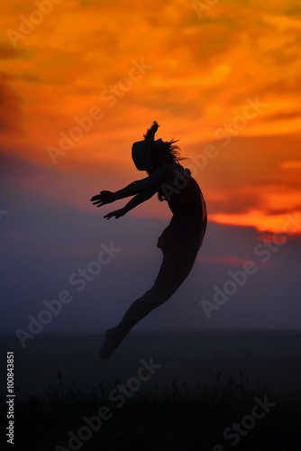young woman jumping on the beach in summer evening