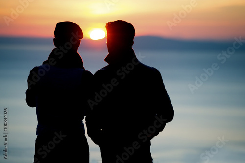 Silhouette of men watching sunset 