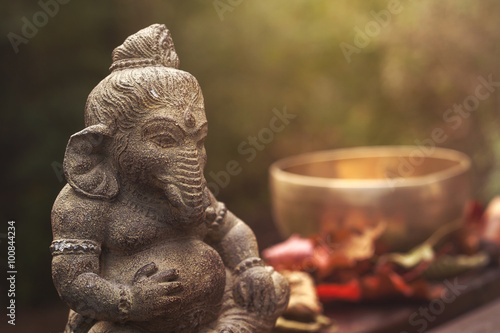 ganesha deity stone statue and singing bowl on the background