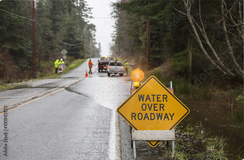 Photo Emergency workers placing warning signs on flooded road
