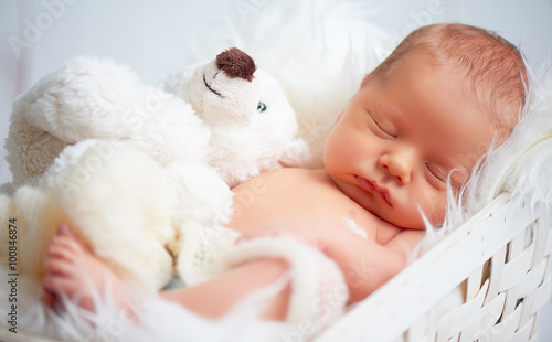 Cute newborn baby sleeps with toy teddy bear
