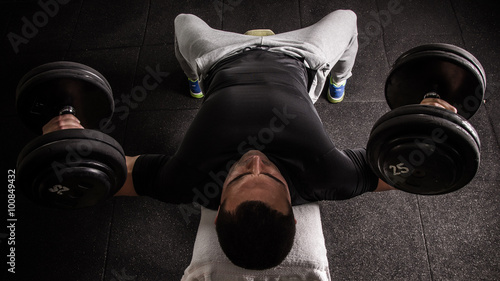 Muscular man exercise on incline bench with dumbbells