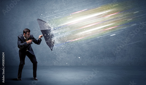 Business man defending light beams with umbrella concept photo