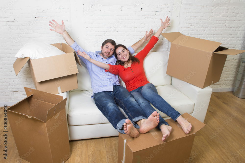 young happy American couple lying on couch together celebrating moving to new house unpacking cardboard boxes young happy American couple lying on couch together celebrating moving to new house unpacking cardboard boxes
