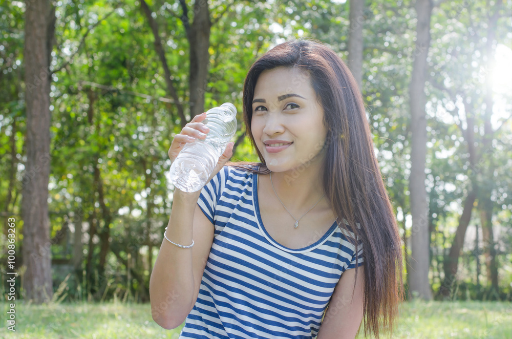 Beautiful Asian woman holding a bottle of water in park Beautiful Asian woman holding a bottle of water in park