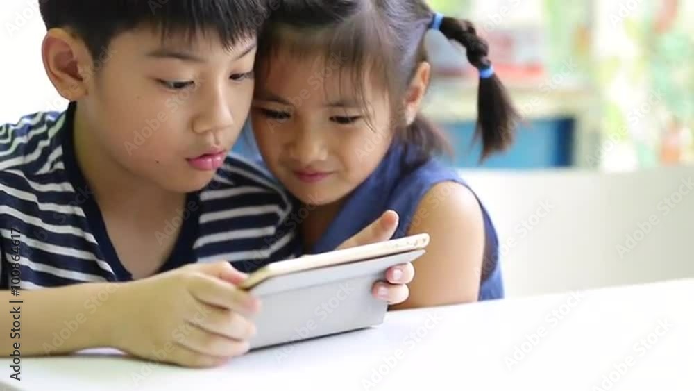 Little asian boy with tablet computer and little girl playing together Little asian boy with tablet computer and little girl playing together