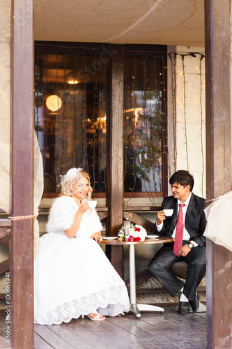 Bride and groom drinking coffee at an outdoor cafe