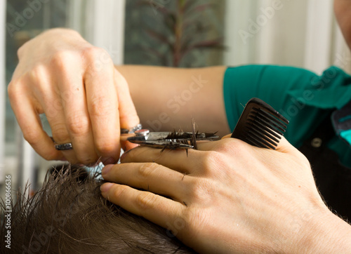 hairdresser cuts hair with scissors on crown of. handsome satisfied client in professional hairdressing salon