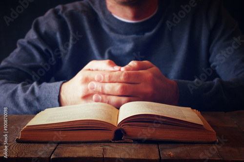 low key image of person sitting next to prayer book 