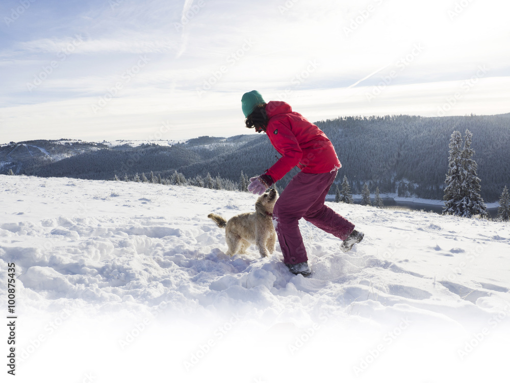 girl playing with dog in winter snow 