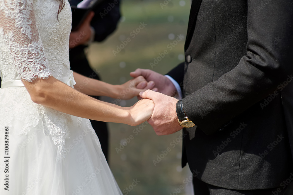 bride and groom holding hands in a summer park