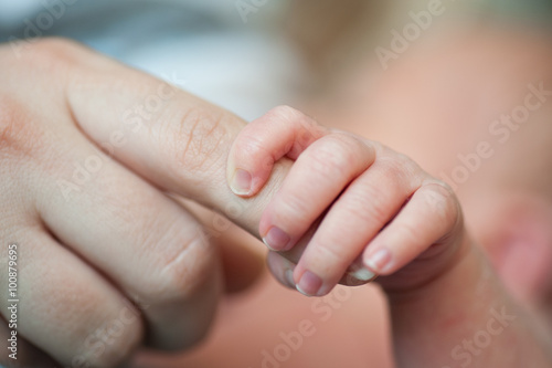 Close-up of baby's hand holding mother's finger with tenderness