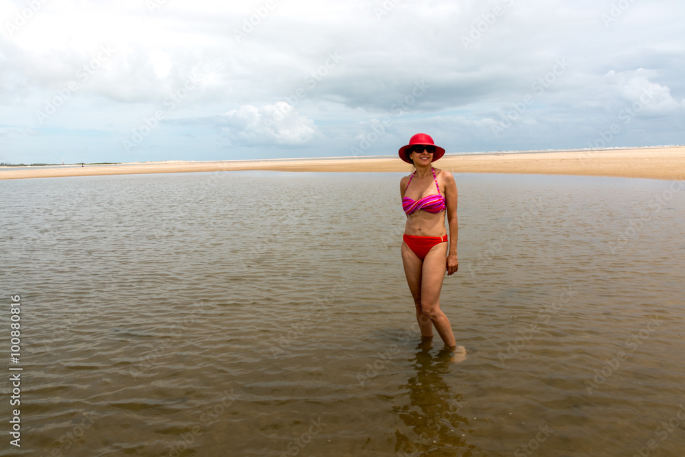 Women In Bikini with Red Hat on a Lone Stretch of Beach 