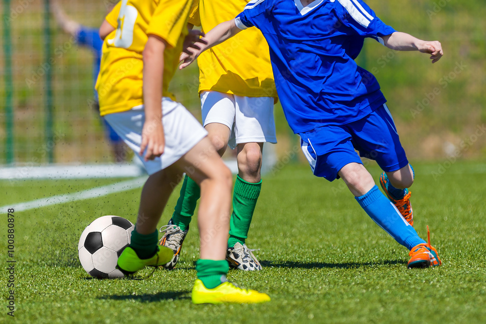 Training and football match of youth soccer teams. Young boys playing soccer game. Players running and kicking soccer ball. Game of tournament for kids. Running players in blue and yellow uniform. Training and football match of youth soccer teams. Young boys playing soccer game. Players running and kicking soccer ball. Game of tournament for kids. Running players in blue and yellow uniform.