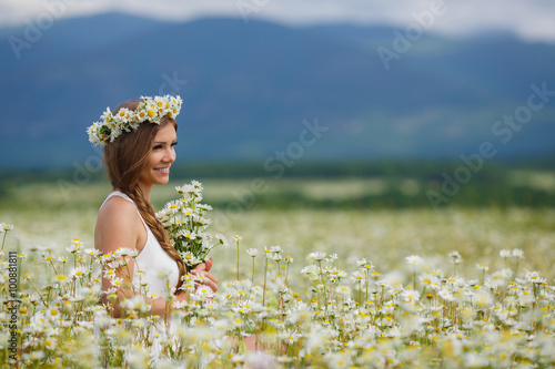 Beautiful young woman in a field of blooming daisies