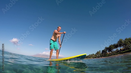 Fit Young Man Stand Up Paddle Boarding in Summer  photo