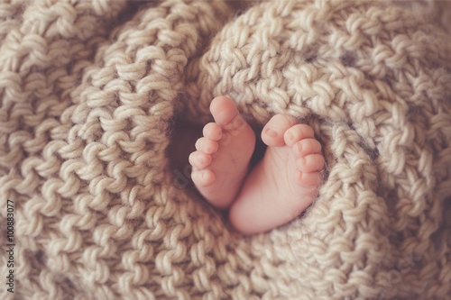Little feet a newborn baby in a beige blanket