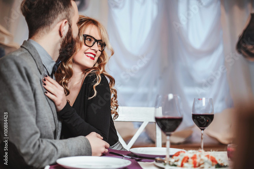 Beautiful young couple with glasses of red wine in luxury restaurant
