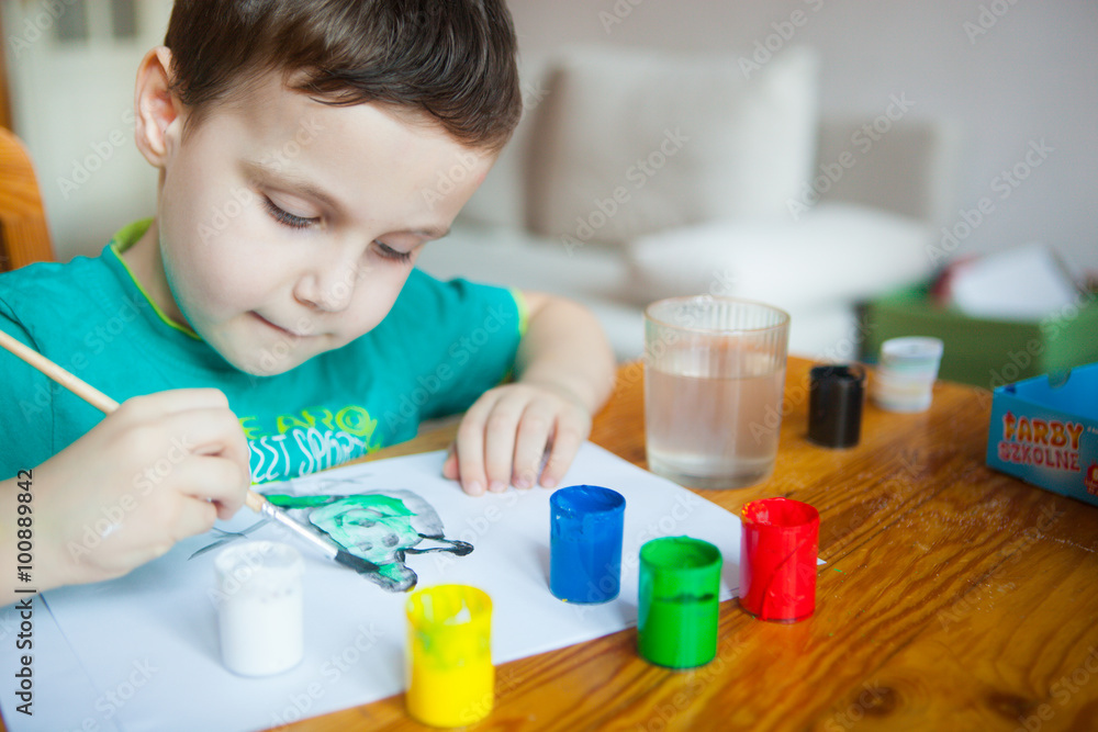 Happy cheerful child drawing with brush in album using a lot of painting tools. Creativity concept. Happy cheerful child drawing with brush in album using a lot of painting tools. Creativity concept.