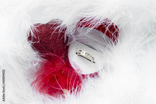 Happy Valentine’s day. Gift box with red heart and wedding ring on among the feathers photo