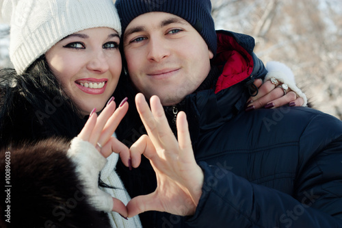 Young couple holding hands heart. outdoors in winter