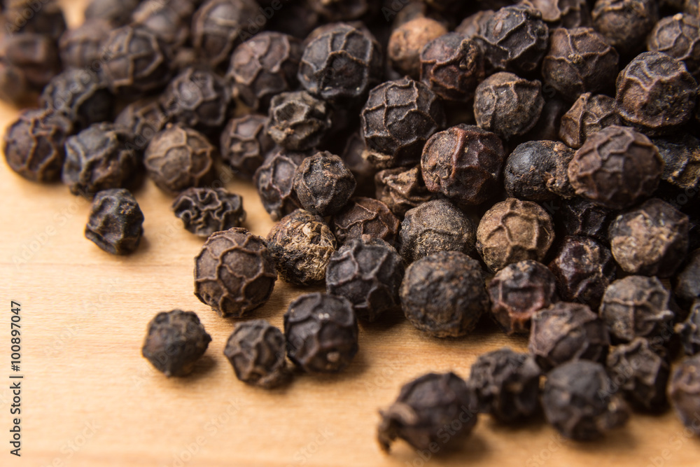 Heaps of aromatic black pepper corns on wooden surface Heaps of aromatic black pepper corns on wooden surface