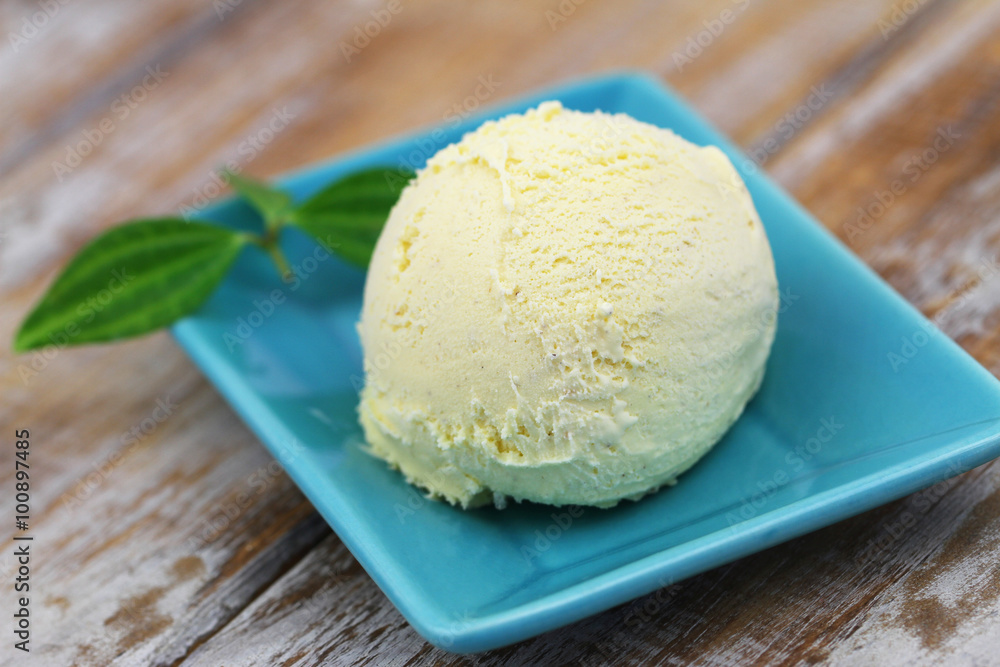 Scoop of fresh vanilla ice cream on green plate on rustic wooden surface
