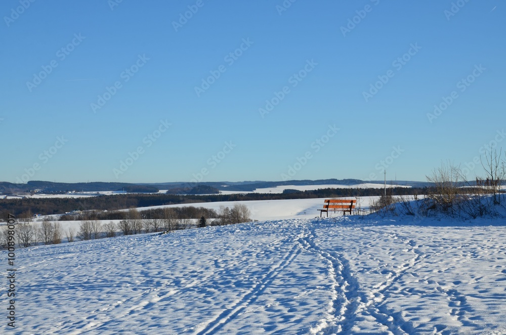 Holzbank in winterlicher Hügellandschaft