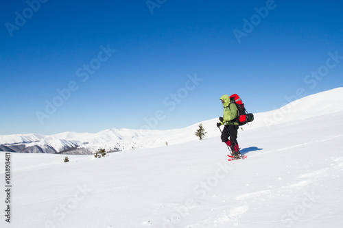 Winter hiking in the mountains on snowshoes with a backpack and tent.