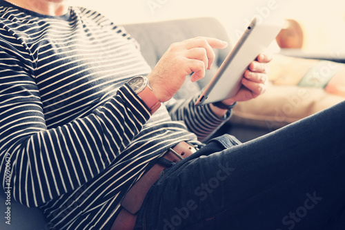 Young man sitting using a tablet, Dressed casually. Vintage post processed. Urban life style, technology, online, business, shopping, fashion and job hunting concept.