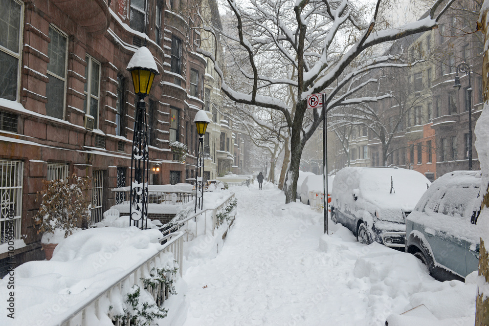 Fototapeta premium Pokryte śniegiem ulicy z kamienic Brownstone w pobliżu Central Parku podczas śnieżycy w Nowym Jorku
